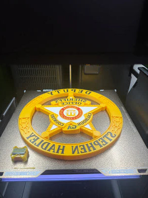 Yellow deputy sheriff's badge with 'Stephen Hadley' on a metallic surface
